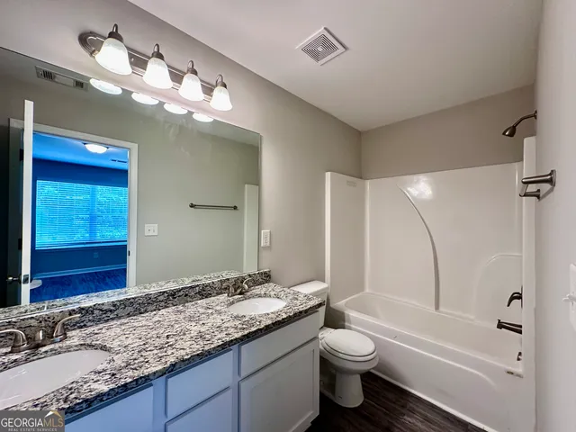 a bathroom with a granite countertop toilet sink and mirror