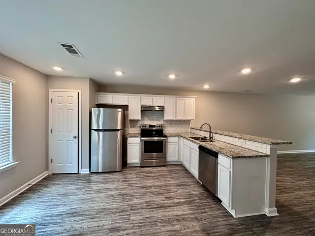 a kitchen with stainless steel appliances granite countertop a refrigerator and a stove top oven