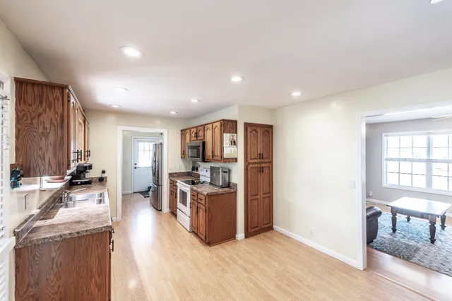 a living room with stainless steel appliances furniture and a kitchen view