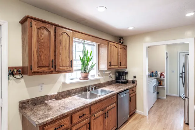 a kitchen with granite countertop a sink a counter space appliances and cabinets