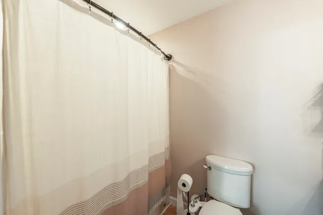 a white toilet sitting next to a shower