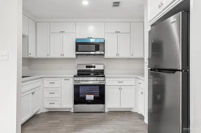 a kitchen with white cabinets and stainless steel appliances
