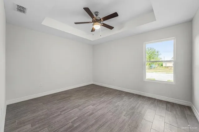 an empty room with wooden floor and ceiling fan