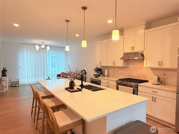 a kitchen with a dining table chairs sink and white cabinets