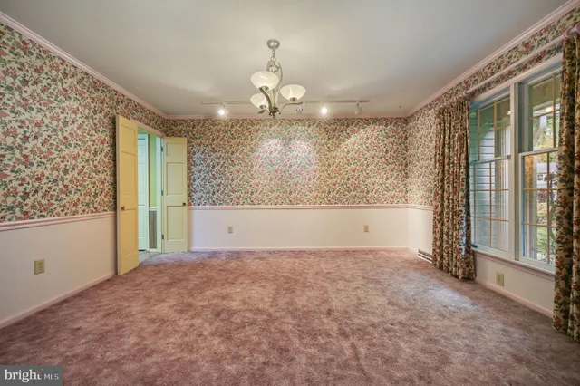 a view of an empty room with window and chandelier fan