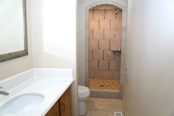 a bathroom with a granite countertop sink a toilet and shower