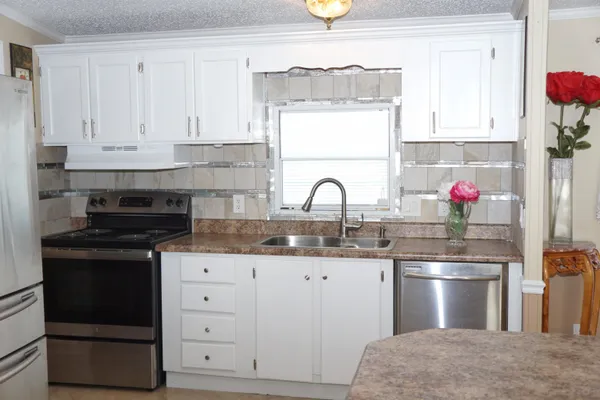 a kitchen with granite countertop a sink stainless steel appliances and cabinets