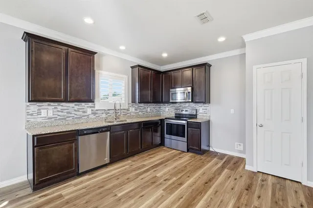 a large kitchen with stainless steel appliances granite countertop a stove and a sink