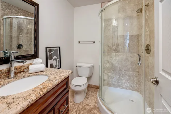 a bathroom with a granite countertop sink toilet and shower
