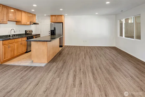 a kitchen with stainless steel appliances granite countertop a sink a stove counter space and wooden floor