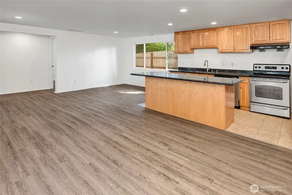a kitchen with granite countertop a sink window and cabinets