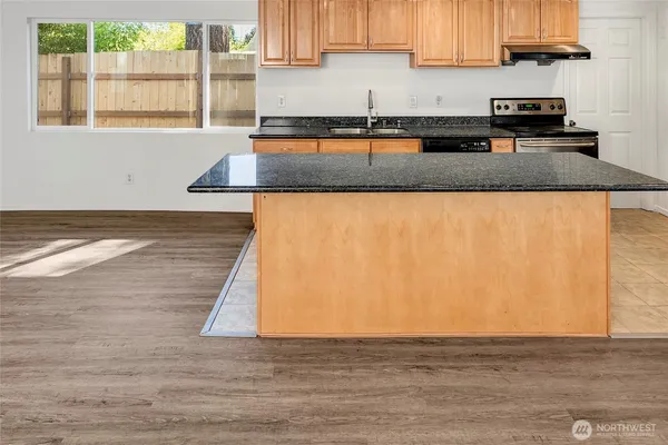 a kitchen with stainless steel appliances granite countertop a sink a refrigerator and wooden cabinets