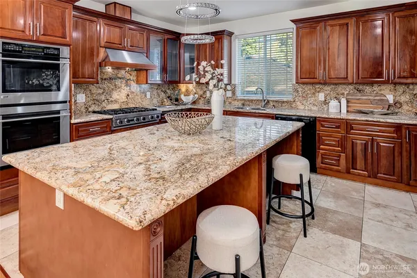 a kitchen with stainless steel appliances granite countertop wooden cabinets a stove top oven a sink and dishwasher