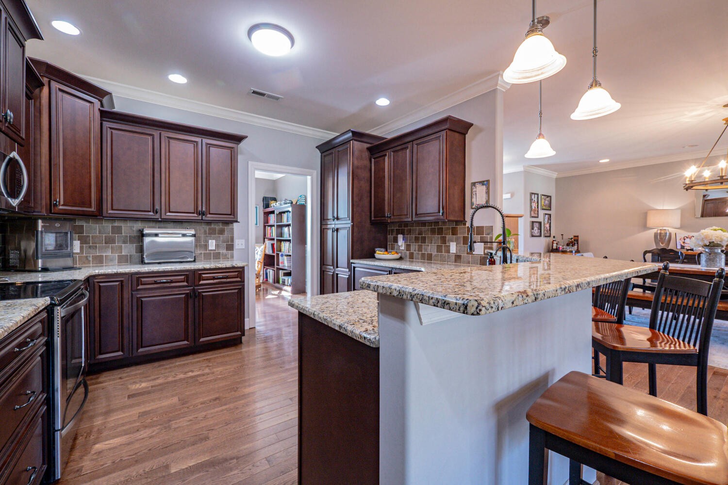 5125 Old Harding Road Franklin, TN 37064 - Photo 16 of 50 a kitchen with kitchen island granite countertop wooden floors wooden cabinets a refrigerator and a stove