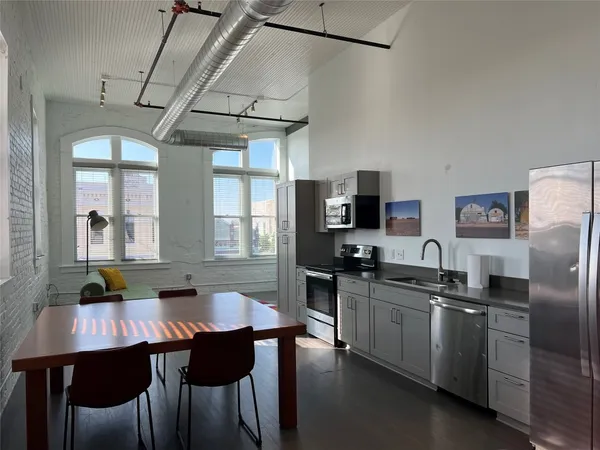 a kitchen with stainless steel appliances granite countertop a sink a stove a refrigerator a dining table and chairs