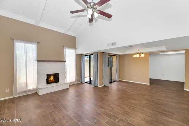 an empty room with wooden floor fireplace and windows