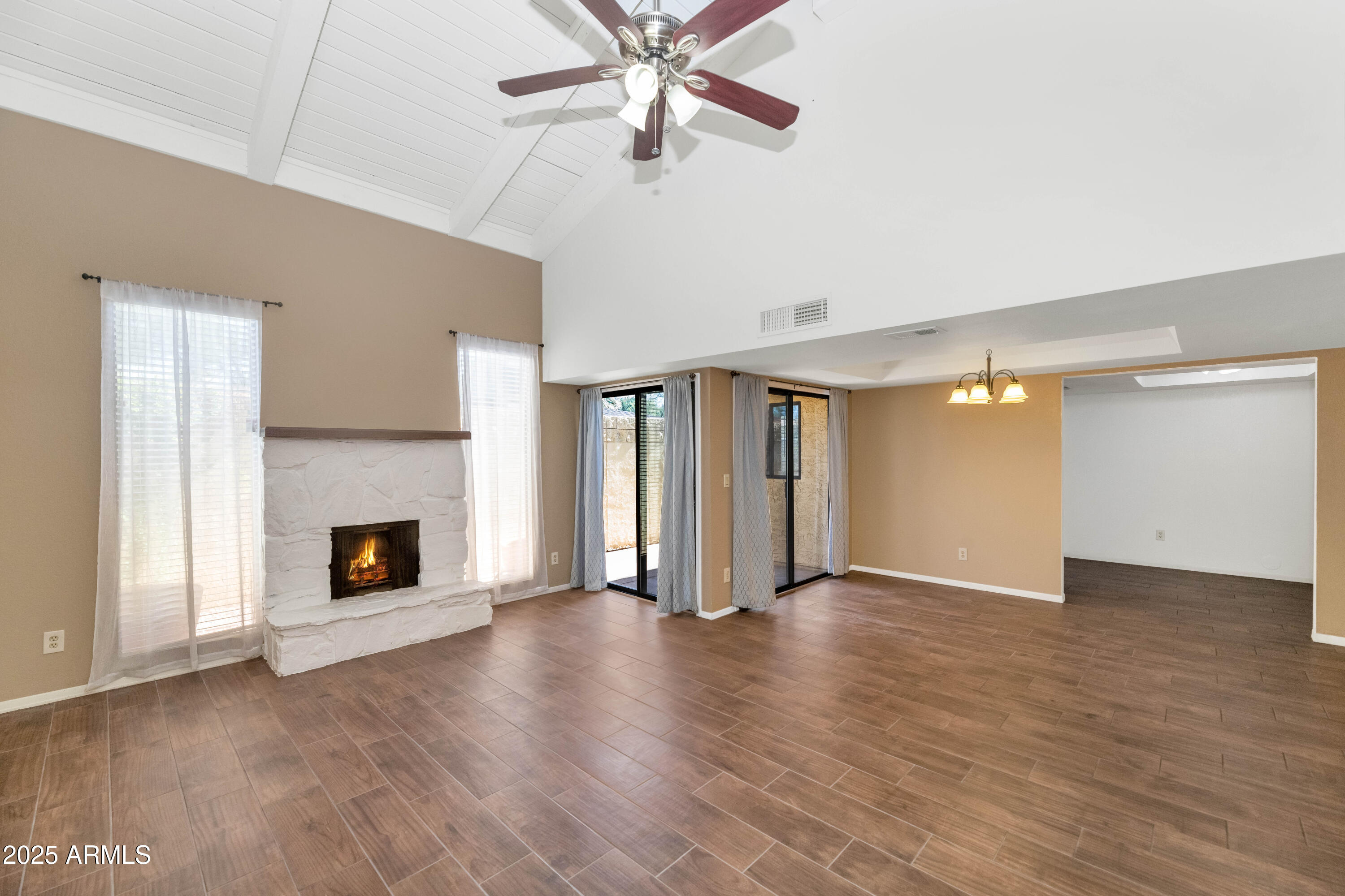 an empty room with wooden floor fireplace and windows