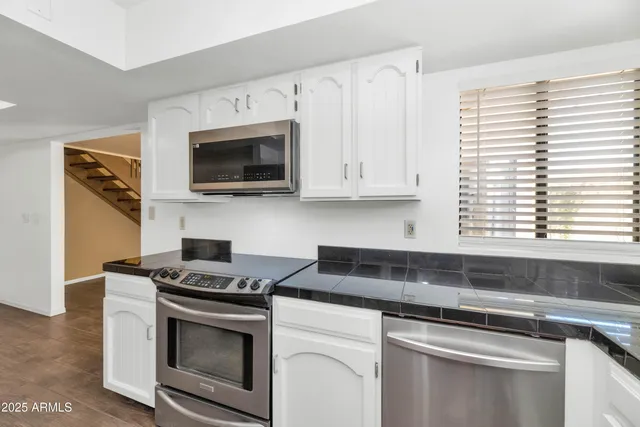 a kitchen with stainless steel appliances granite countertop white cabinets and a stove top oven