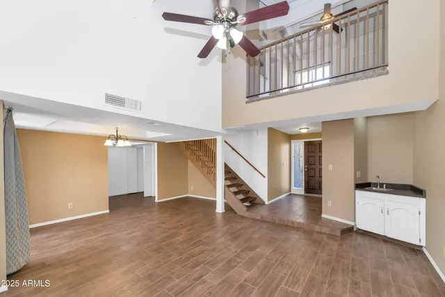 a view of an empty room with stairs and a ceiling fan