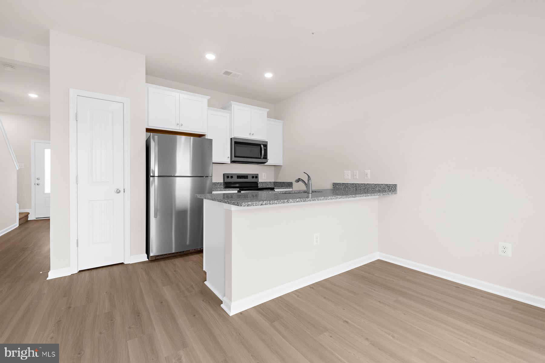 8155 Bartholomew Court Baltimore, MD 21206 - Photo 9 of 19 a kitchen with a refrigerator a microwave oven a sink and dishwasher with wooden floor