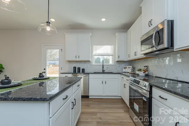 a kitchen with granite countertop a sink stainless steel appliances and cabinets
