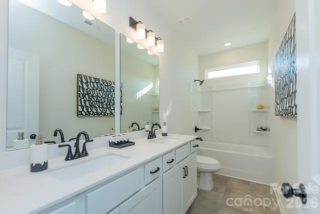 a bathroom with a double vanity sink toilet mirror and shower