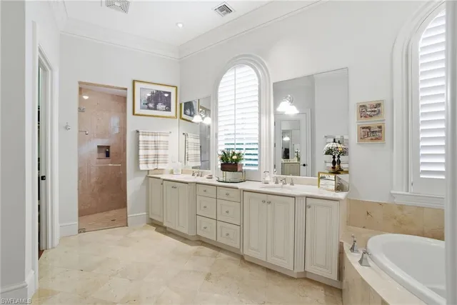 a spacious bathroom with a double vanity sink a mirror a bathtub and next to a window