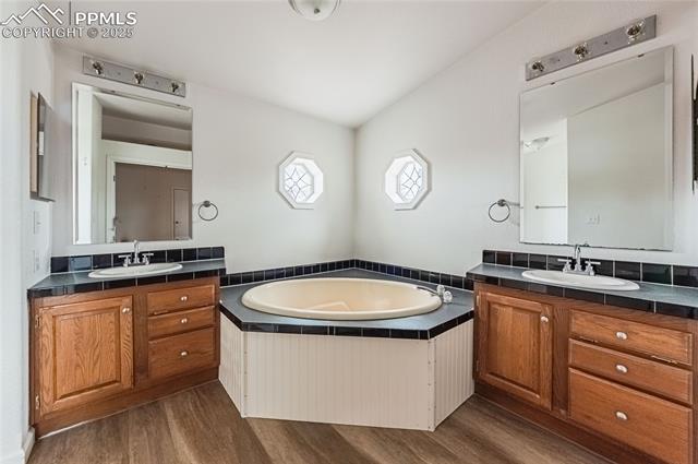 22885 Handle Road Calhan, CO 80808 - Photo 11 of 38 Full bathroom with wood finished floors, two vanities, and a bath