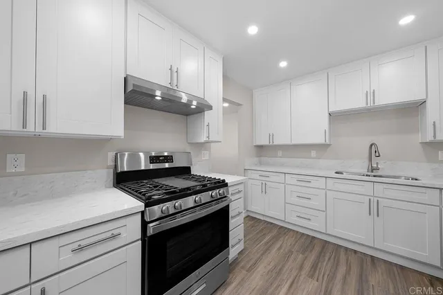 a kitchen with white cabinets stainless steel appliances and wooden floor