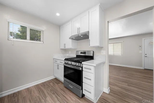 a kitchen with a stove and a wooden floor