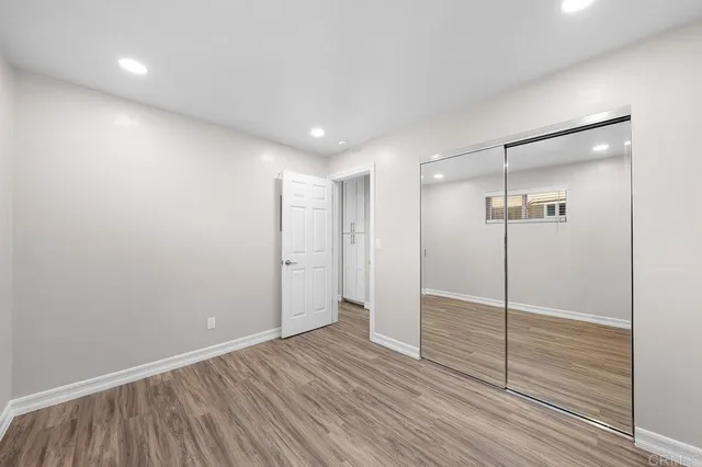 a view of an empty room with wooden floor and a bathroom