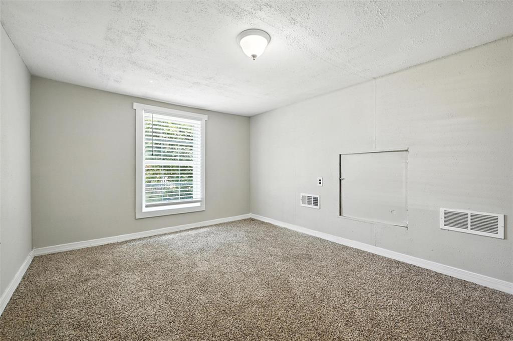 204 Graham Avenue Bonham, TX 75418 - Photo 12 of 21 Carpeted spare room featuring baseboards and a textured ceiling