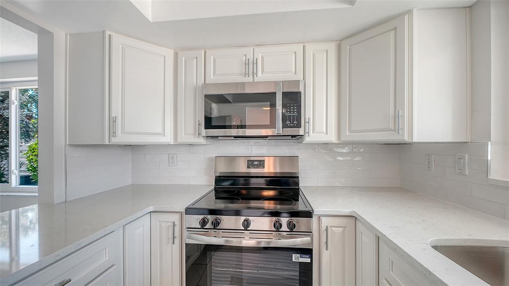 554 Spanish Drive South Longboat Key, FL 34228 - Photo 12 of 72 a kitchen with stainless steel appliances granite countertop white cabinets and a stove a oven with white countertops