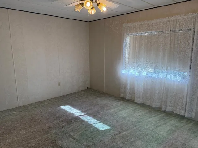 an empty room with a ceiling fan and wooden floor