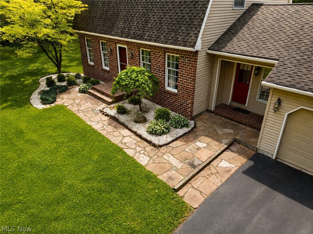 6155 Gibson Road Canfield, OH 44406 - Photo 4 of 43 Exterior featuring red brick and light-colored siding, a flagstone walkway, and landscaped garden beds with white decorative stone