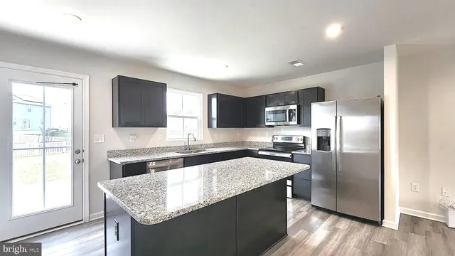 a kitchen with granite countertop stainless steel appliances a sink stove and refrigerator