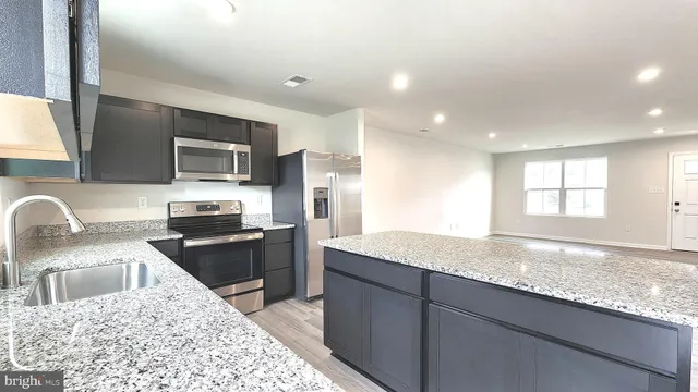 a kitchen with granite countertop kitchen island stainless steel appliances a sink stove refrigerator and a window