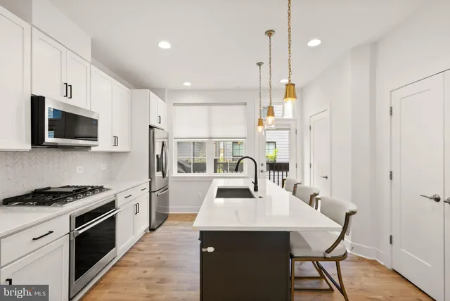 a kitchen with stainless steel appliances white cabinets and a stove a refrigerator with wooden floors