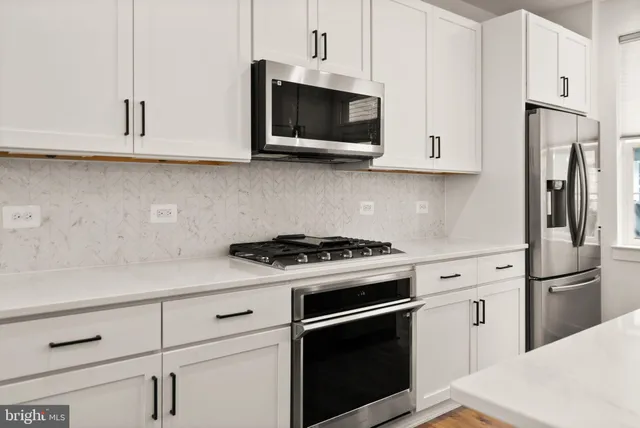 a kitchen with granite countertop white cabinets and stainless steel appliances