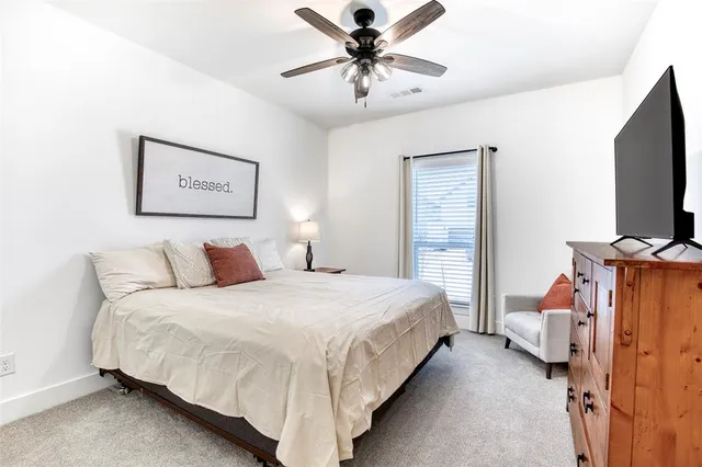 a bedroom with a bed and a flat tv screen on dresser