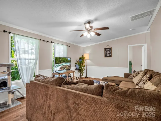 a living room with couches and a ceiling fan with wooden floor
