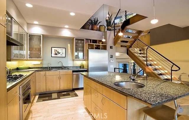 a kitchen with granite countertop a stove a sink and a refrigerator