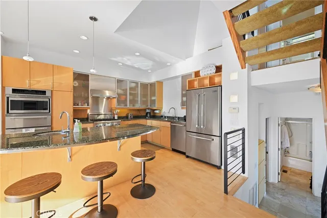 a kitchen with stainless steel appliances granite countertop a sink a stove and a refrigerator