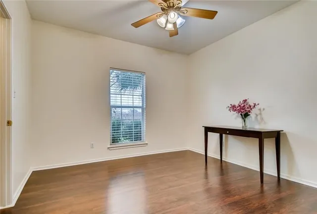 a view of an empty room with a window and wooden floor