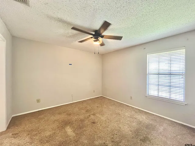 an empty room with windows and fan