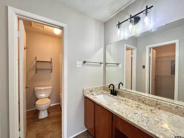 a bathroom with a granite countertop sink toilet and shower curtains