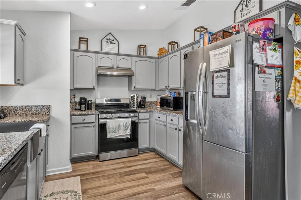13146 Mohawk Road Apple Valley, CA 92308 - Photo 6 of 15 a kitchen with stainless steel appliances granite countertop a refrigerator a stove and a sink with dishwasher