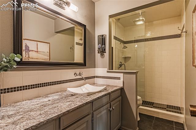 7175 Higher Ridges Court Colorado Springs, CO 80919 - Photo 18 of 50 Bathroom featuring vanity, toilet, tile patterned floors, and tiled shower