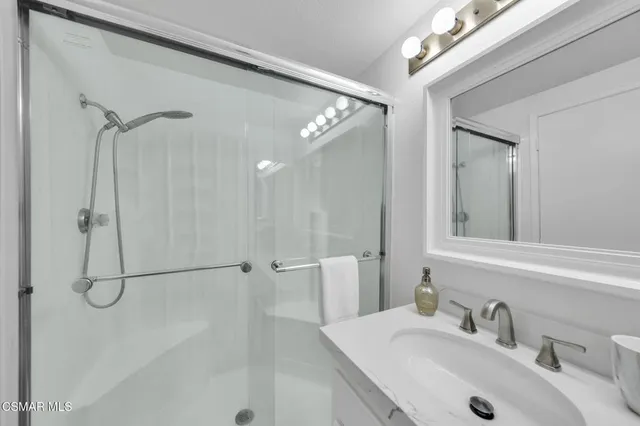 a bathroom with a sink shower and a mirror