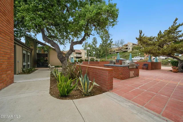 a view of a patio with table and chairs potted plants and large tree